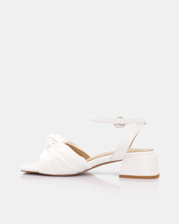 White sandal with a block heel on a light gray background