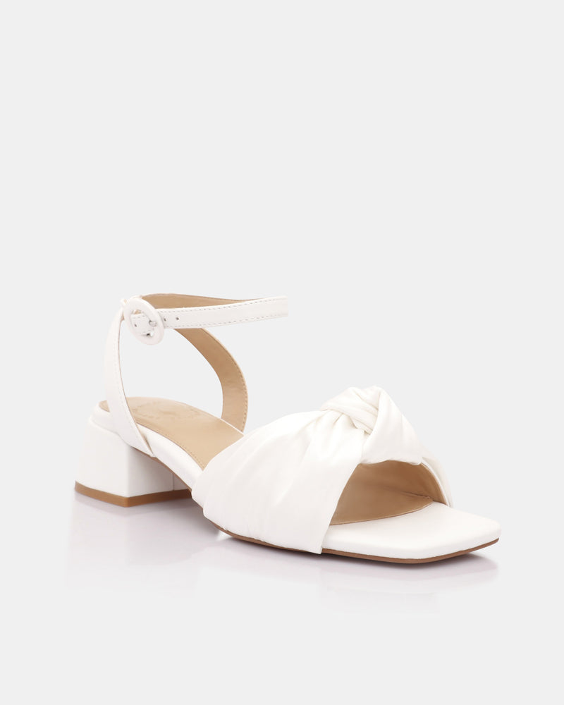 White sandal with a block heel on a light gray background