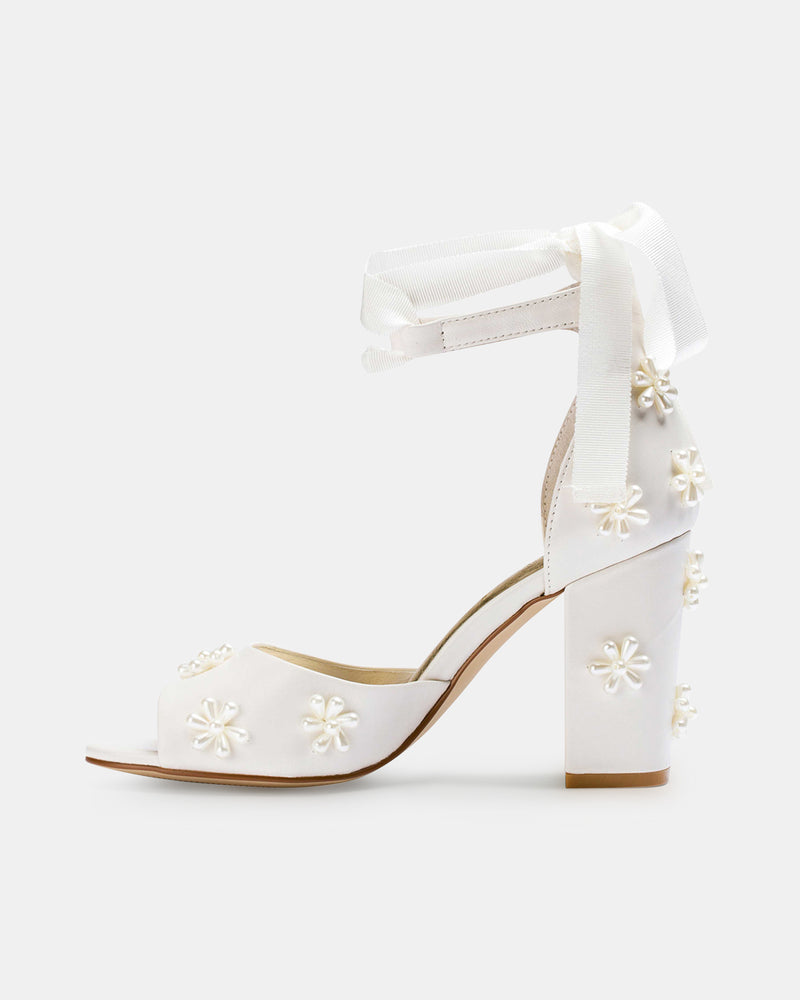 White high-heeled shoes with floral designs on a white background