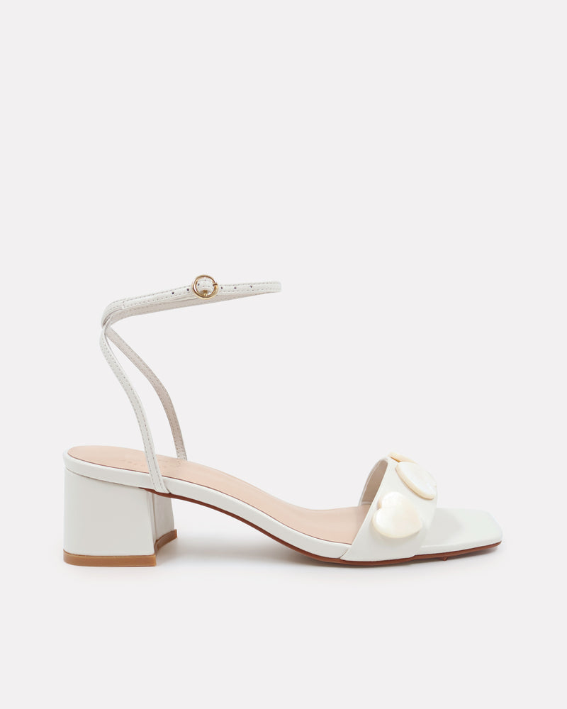 White sandal with pearl details on a white background