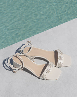 White sandal with floral designs on a pool background