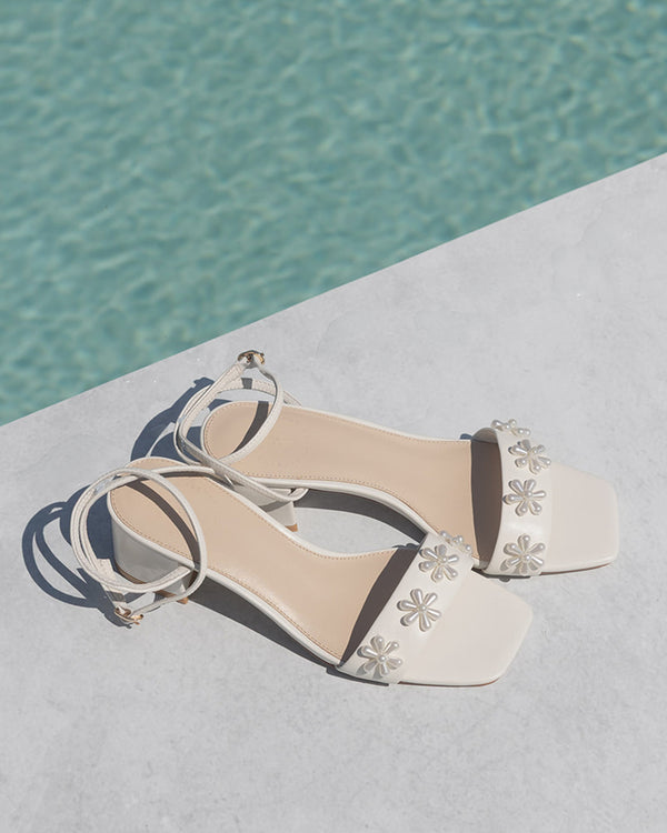 White sandal with floral designs on a pool background