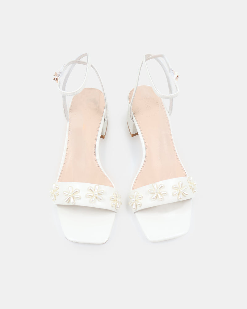 White sandal with floral designs on a white background