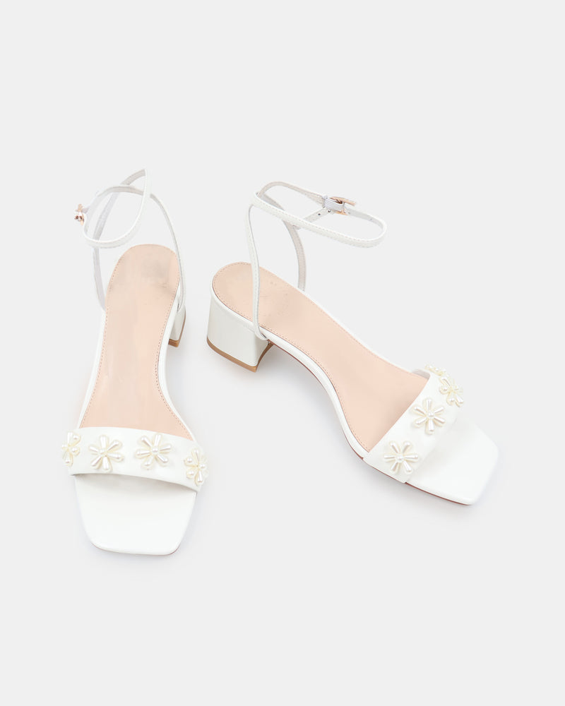 White sandal with floral designs on a white background