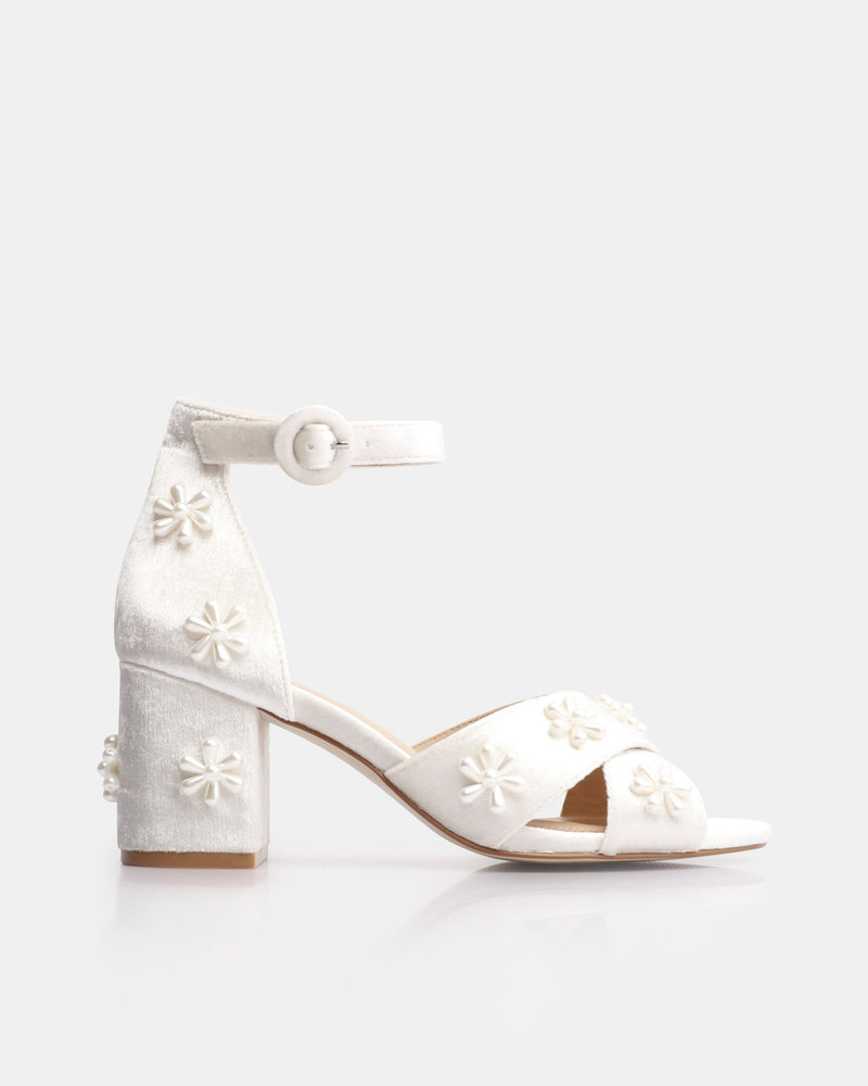 White high-heeled shoes with floral designs on a white background