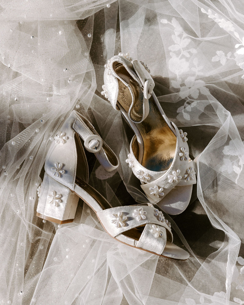 White wedding shoes with decorative elements on a sheer fabric background
