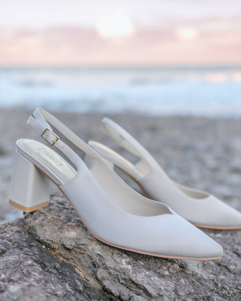 White high-heeled shoes on a rock with a beach background
