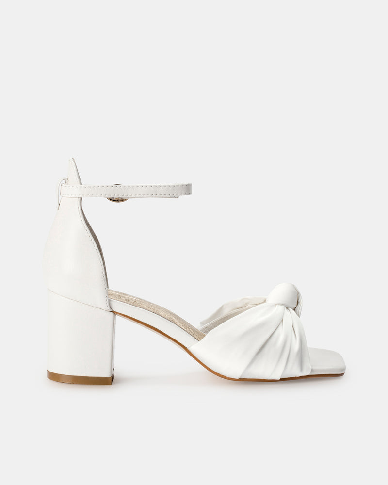 White sandal with block heel and bow detail on a white background