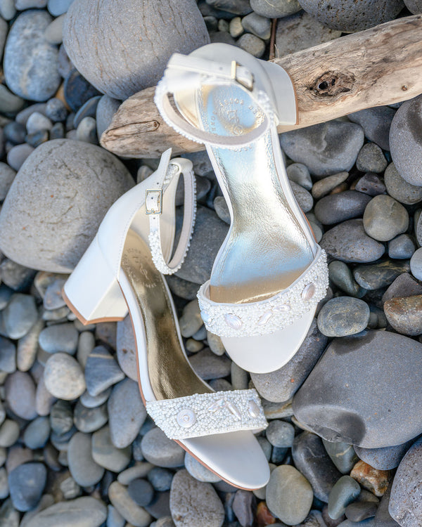 ivory high-heeled sandals with rhinestone straps on pebbles