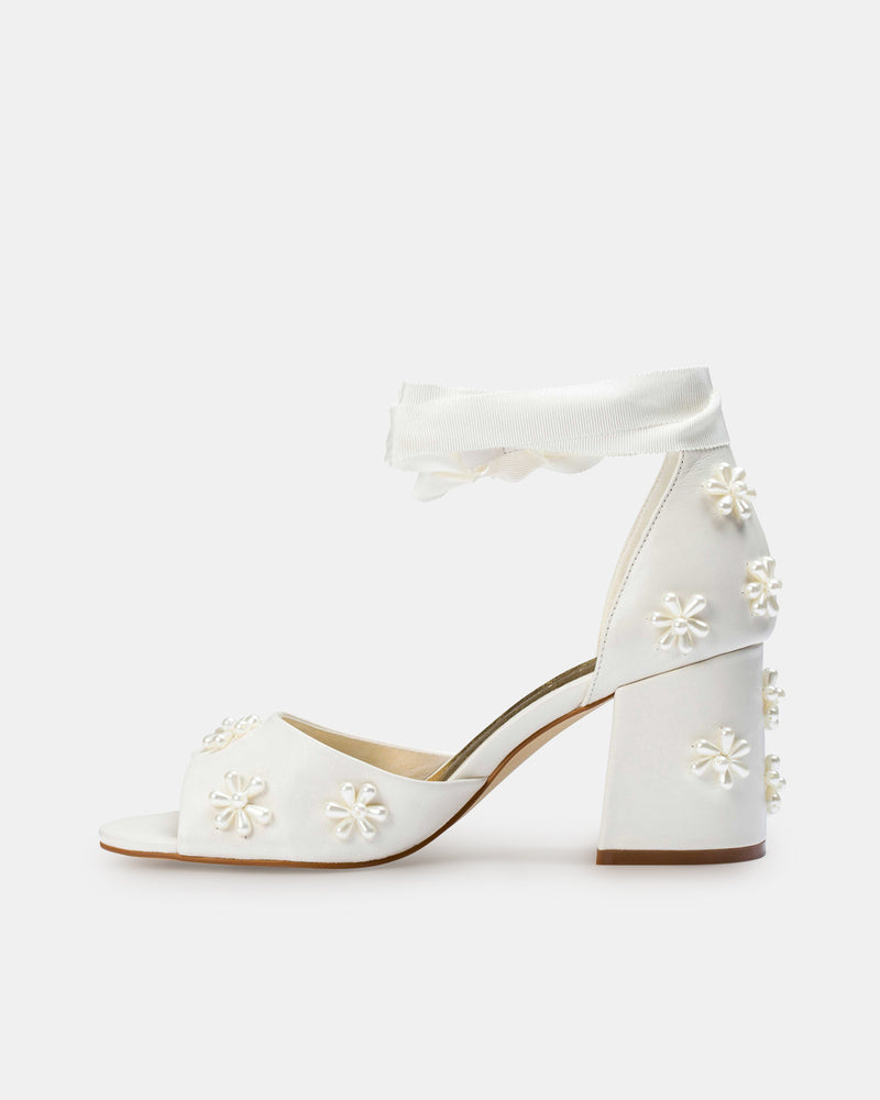 White high-heeled shoes with floral designs on a white background