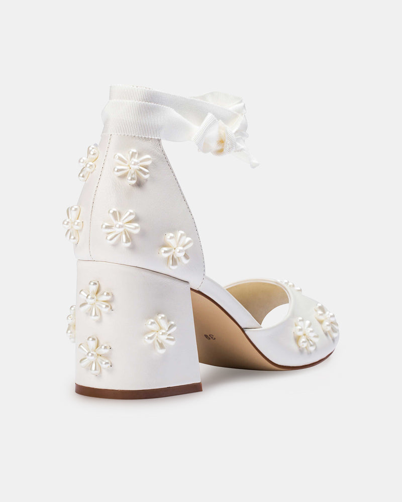 White high-heeled shoes with floral embellishments on a white background
