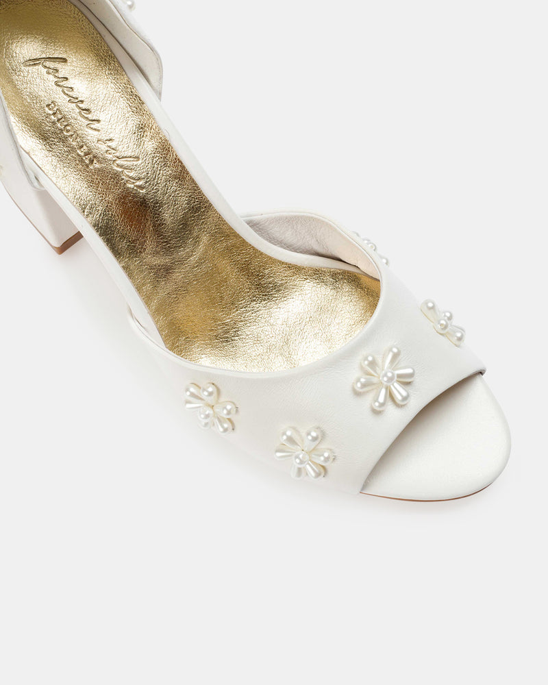 White shoe with gold interior and floral embellishments on a white background