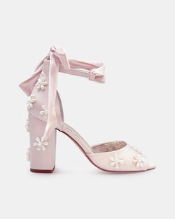 Pink high-heeled shoes with floral decorations on a white background