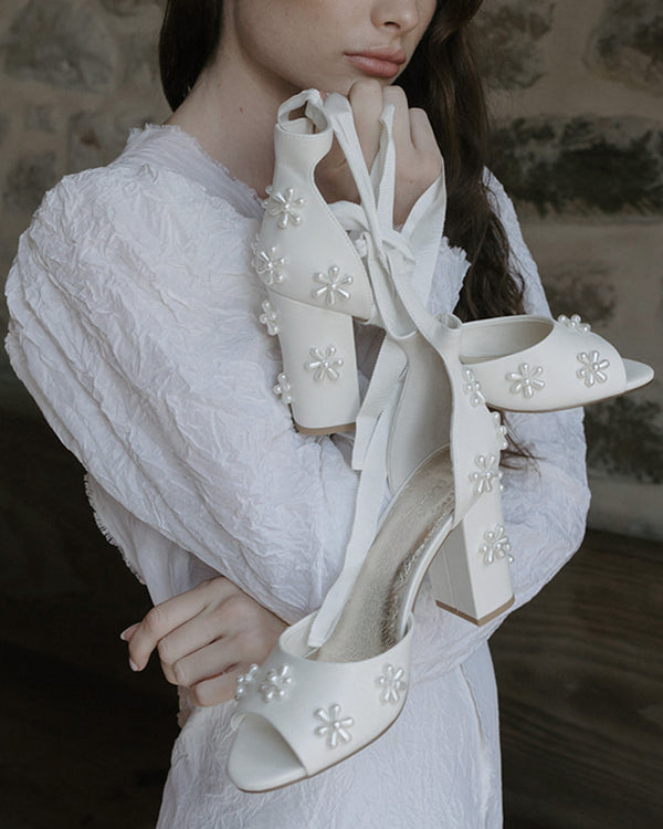 White high-heeled shoes with floral embellishments