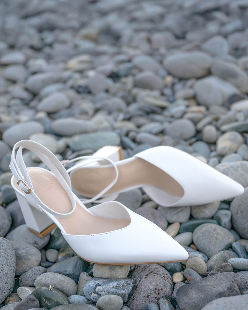 White high-heeled shoes on a pebbly surface