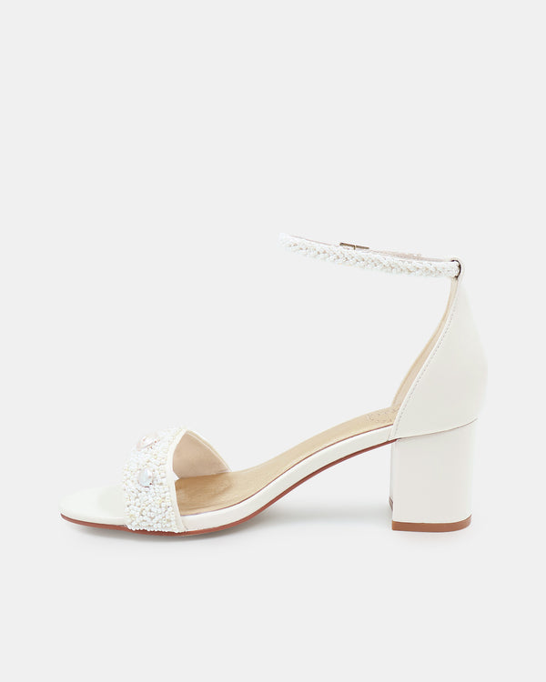 White sandal with block heel and embellishments on a white background