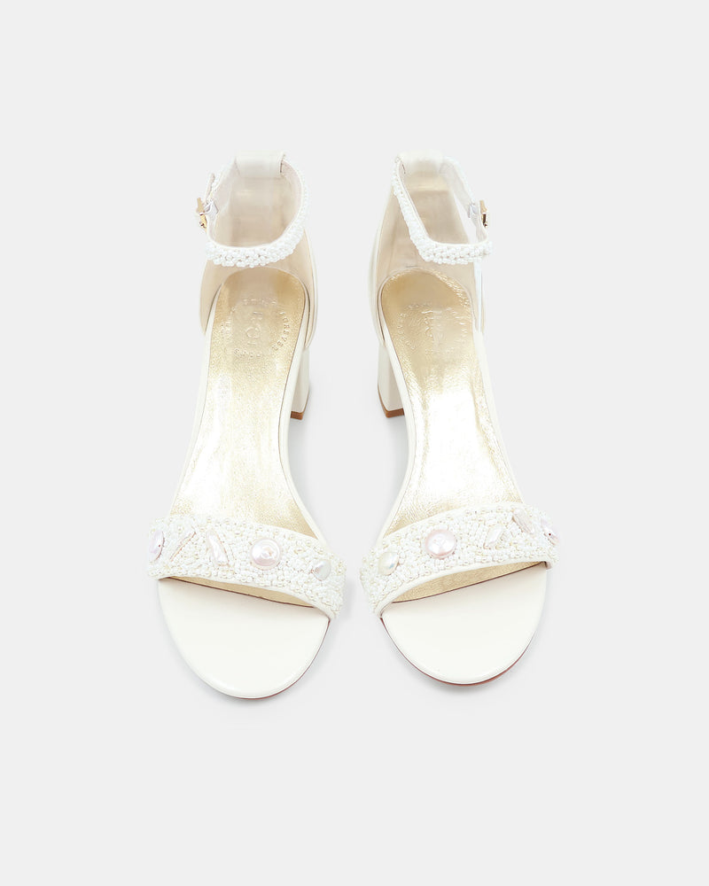 Pair of white high-heeled sandals with lace details on a white background