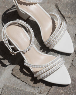 Ivory sandal with block heel and ankle strap on a rock background