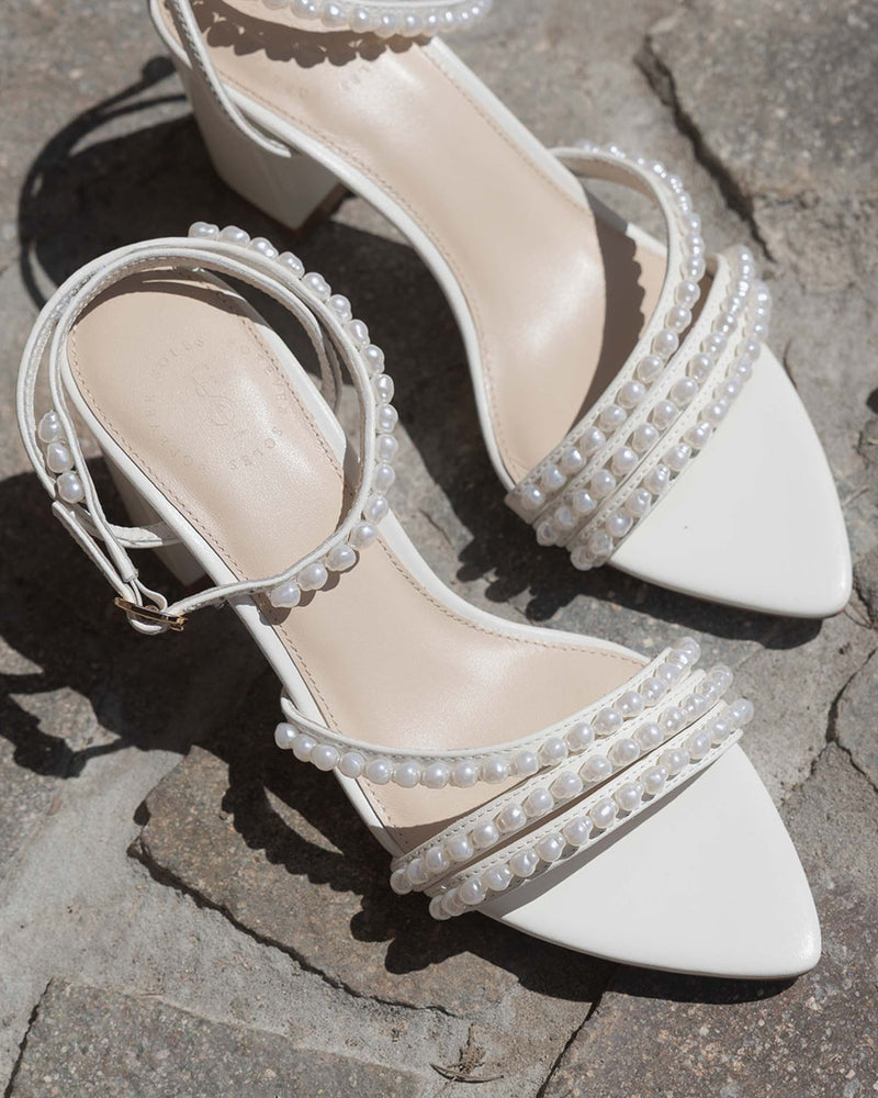 Ivory sandal with block heel and ankle strap on a rock background