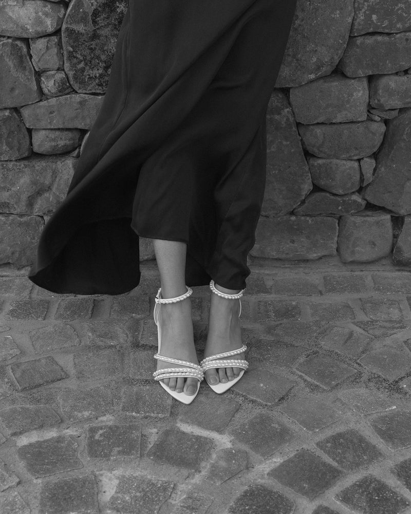 Ivory sandal with block heel and ankle strap on a rock background